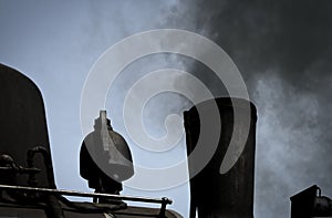 Detailed view of a black historic steam locomotive blowing black rusty smoke out of a chimney, transport, black and white