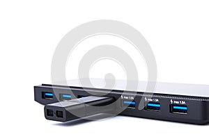 Detailed view of black USB hub with many ports, charging and flash drive with silver blue connector. On white background with