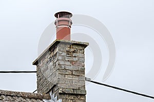 Detailed view of chimney seen on a cottage roof with fitted bird cowl.