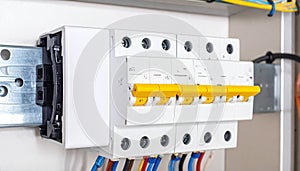Electrical circuit breakers with yellow levers and wires in a modern distribution box electrical panel