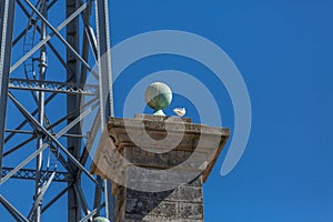 Detailed view at the granite pillar with sphere on top, D. Luis bridge structure and blue sky as background