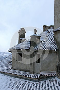 Detailed view of red tile roof in the snow. Ancient Bran Castle, also called Dracula`s Castle.