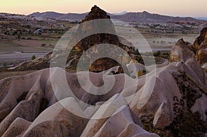 Detailed view of shaped sandstone rocks against sunset sky. Typical geologic formations of Cappadocia. Mountains in the light haze