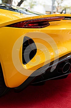 Detailed view of sports car's exhaust pipe and ventilation scoops located below tail light with extraordinary shape