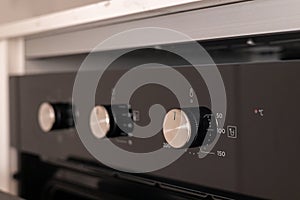 Close-up of oven temperature control knobs in a modern kitchen interior