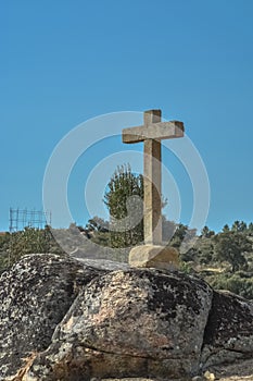 Detailed view at the stone crucifix sculpture, blue sky and field of trees on background