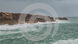 Detailed view of volcanic coastline with high cliffs and waves breaking over volcanic rocks, Portugal.