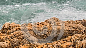 Detailed view of volcanic coastline with high cliffs and waves breaking over volcanic rocks, Portugal.