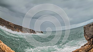 Detailed view of volcanic coastline with high cliffs and waves breaking over volcanic rocks, Portugal.