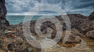 Detailed view of volcanic coastline with high cliffs and waves breaking over volcanic rocks, Portugal.