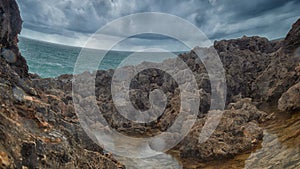 Detailed view of volcanic coastline with high cliffs and waves breaking over volcanic rocks, Portugal.