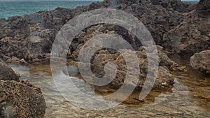 Detailed view of volcanic coastline with high cliffs and waves breaking over volcanic rocks, Portugal.