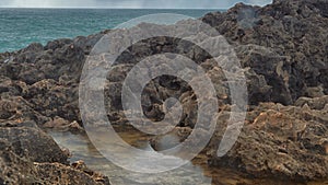 Detailed view of volcanic coastline with high cliffs and waves breaking over volcanic rocks, Portugal.