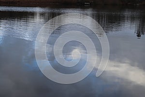 Detailed view on a water surface reflecting the blue sky and some sunlight