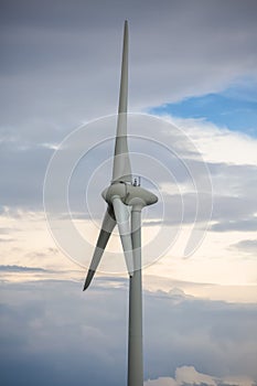Detailed view of a wind turbines on top of mountains, cloudy sky as background