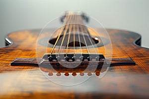 Detailed view of a wooden acoustic guitar focusing on the bridge and strings with a blurred background
