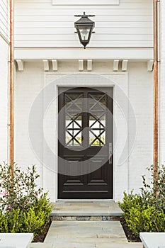 Detailed wooden front door of white brick home