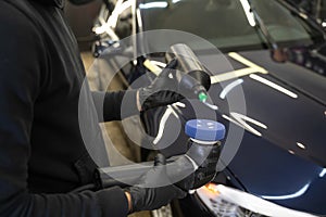 Detailing master applies car polish paste to the polisher. Vehicle paintwork polishing concept.