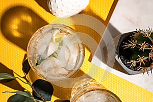 Details of alcoholic drinks and beverages at pub or bar, mojito with ice on yellow background. Top view