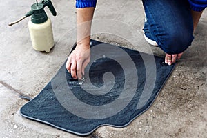 Details of automobile cleaning - male using professional chemical solutions to clean car floor mats