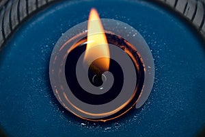 Details of a burning blue candle on a glass container