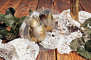 Details captured a brass milk jug and a brass sugar bowl, ivy on an old, wooden table top with coffee beans