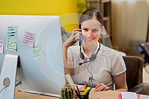 Details capturing video of a smiling cute operator woman working at the call office centre she using the smartphone to