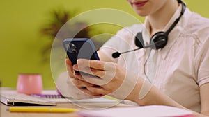 Details capturing video of a smiling cute operator woman working at the call office centre she using the smartphone to