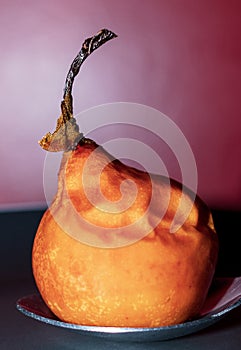 Details caramelized pear, winter dessert, on metal spoon with white plastic handle, on black plate with white edge and red