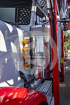 Details of classic big rig semi truck with shiny paint and chrome with line of light and car hauler semi trailer standing on the