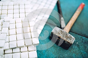 Details of construction tools, bathroom and kitchen renovation - pieces of mosaic ceramic tiles and rubber hammer