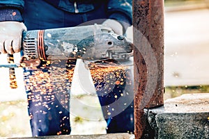 Details of construction worker cutting metal bars using angle grinder.