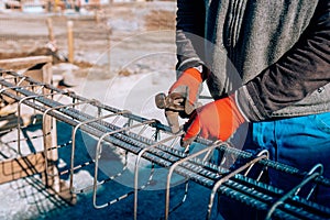 Details of construction worker - hands securing steel bars with wire rod for reinforcement of concrete or cement