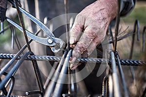 Details of construction worker - hands securing steel bars with wire rod for reinforcement of concrete