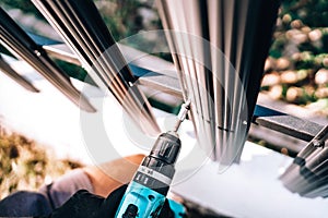 Details of construction worker using electrical screwdriver for fastening screws