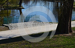 Details of the edge of the pond with paved banks flat stones. curved shape. the path is lined with weeping willows and the sluice