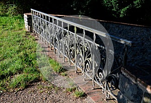 Details of the edge of the pond with paved banks flat stones. curved shape. the path is lined with weeping willows and the sluice