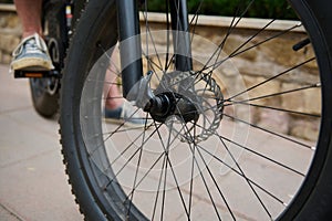 Details on electric bike bicycle wheel with spokes. Cropped view of a man cycling in the nature. Cyclist renting