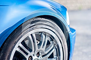 Details of the front right wheel of a fast, blue car