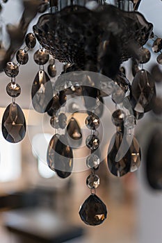 Details of a glass chandelier with a blurred room in the background.