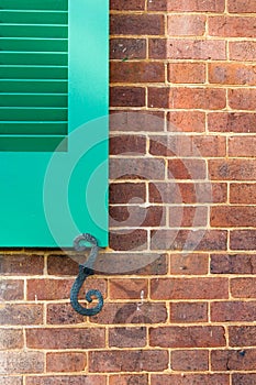 Details of green window shutters and holder on brick wall