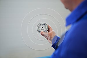 Details with the hand of a worker holding a broken glass PSI manometer