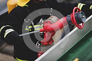 Details with the hands of a firefighter holding a fire suppression system hydrant on a hospital helipad