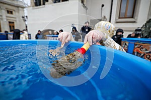 Details with the hands of a high priest of the Romanian Orthodox Church blessing water during the Epiphany mass, with a cross and