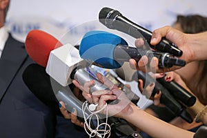 Details with the hands of journalists holding microphones in fron of a politician during a press conference