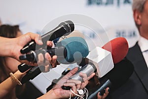 Details with the hands of journalists holding microphones in fron of a politician during a press conference