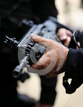 Details with the hands of a man holding an automatic rifle