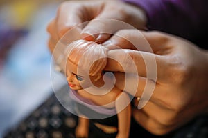 Details with the hands of a mother brushing and arranging the hair of her little daughterâ€™s doll - activities during Covid-19