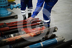 Details with the hands of a worker touching old and rusty heavy iron drilling equipment used in the oil and gas industry