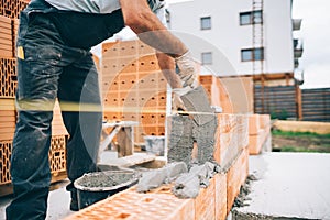 details of industrial bricklayer installing bricks on building construction site